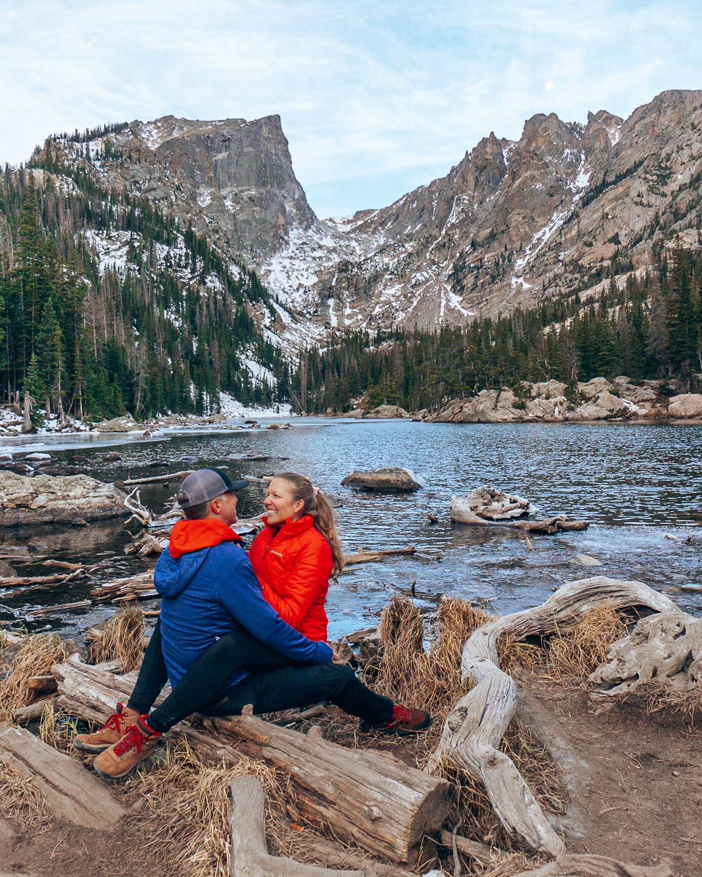 Man and woman look at each other under Flattop Mountain and Hallett Peak at Dream Lake in Rocky Mountain National Park